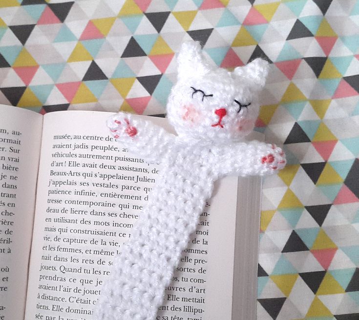 a crocheted cat laying on top of an open book