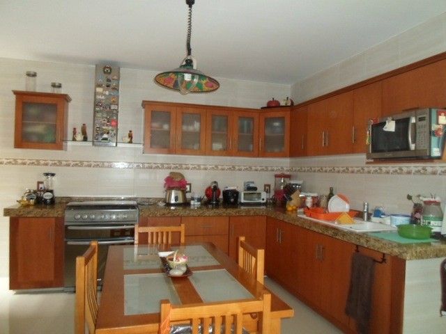 a kitchen filled with wooden cabinets and counter tops next to a stove top oven under a hanging light