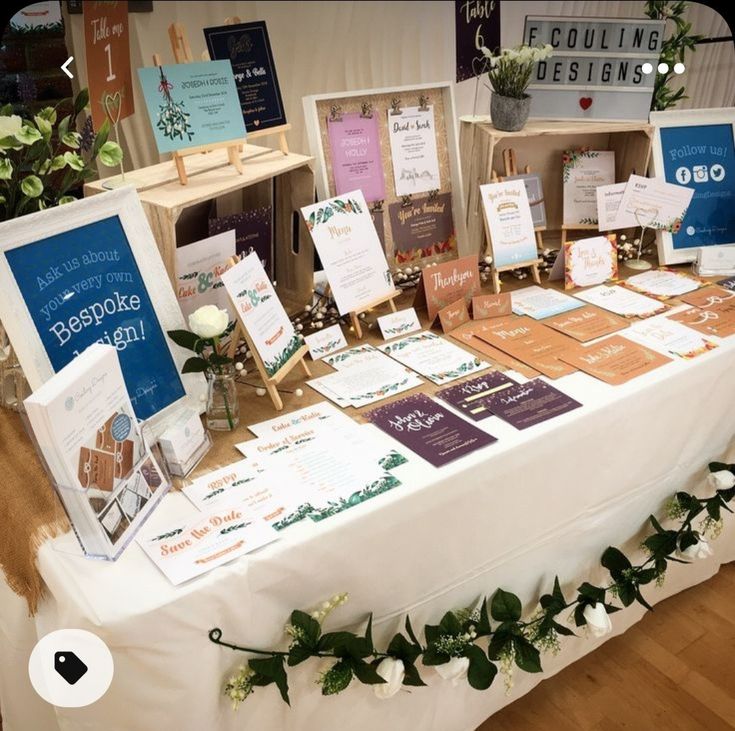 a table topped with lots of cards and flowers on top of a white table cloth