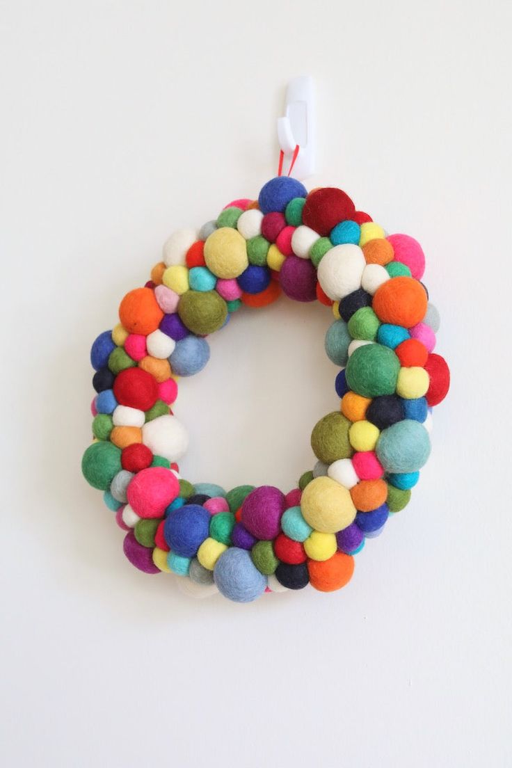 a multicolored felt wreath hanging on a white wall