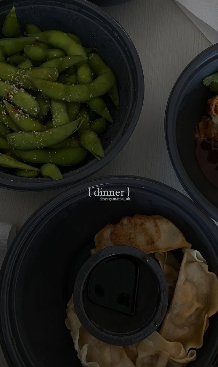 three black bowls filled with different types of food on top of a white tablecloth