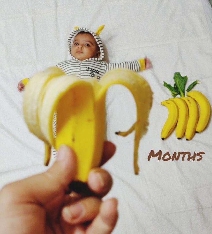 a person holding up a banana with the word q on it and bananas next to them