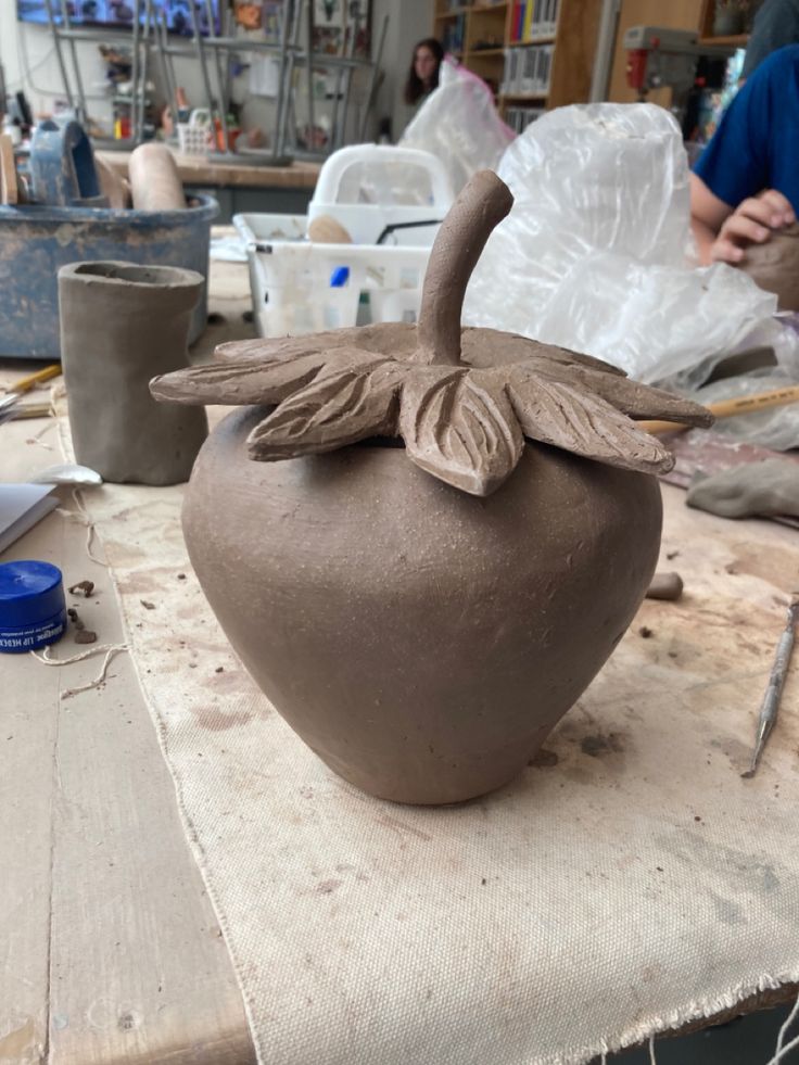 a clay pot with a bird on it sitting on a table next to other items