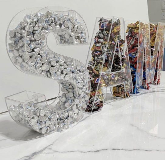 the letter s is made out of candy and plastic wrappers on a marble surface