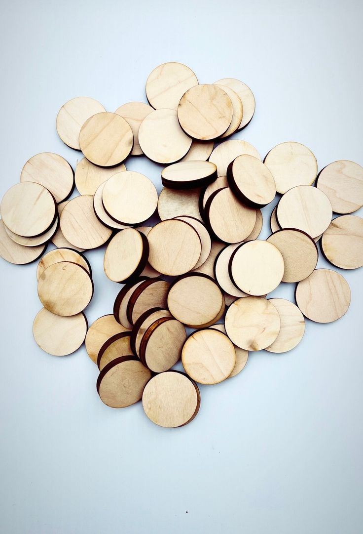 a pile of wooden discs sitting on top of a white table next to each other