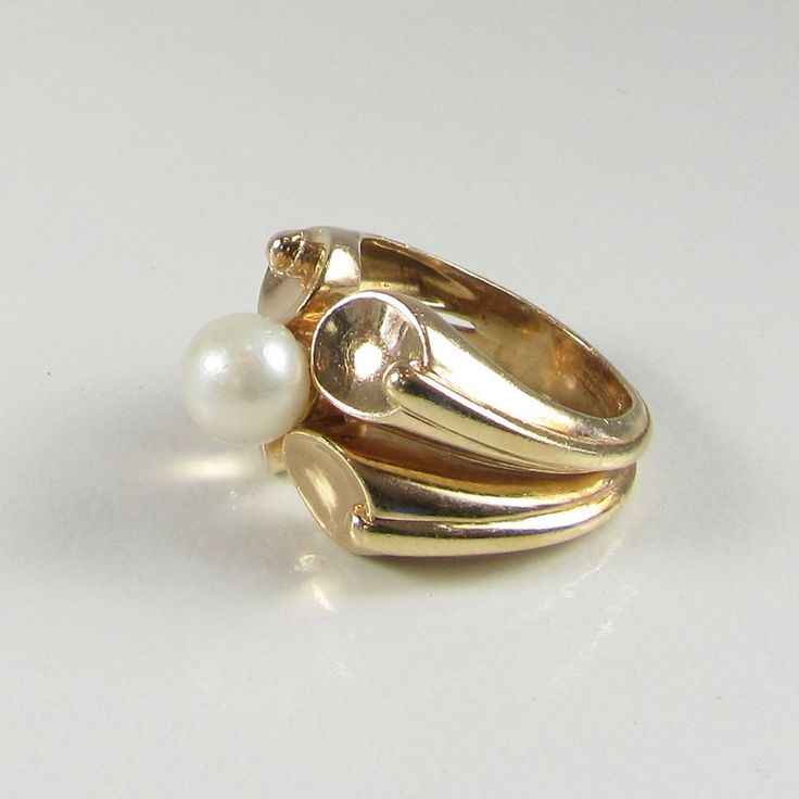 14 karat yellow gold pearl ring. The ring has 4 ovalish-round concave designs and the pearl sits in the middle of those designs. The pearl has a silvery white body color with little to no overtones. The width of the ring (north/south) measures approximately 15.50mm at its widest point. Ring Size: 6 can be sized Circa: Late 1970's early 1980's All rings come with one free sizing...To size the ring down it is completely free...to size the ring up we will pay for the first size, and you will pay th Heirloom Pearl Open Ring For Formal Occasions, Heirloom Style Pearl Open Ring For Formal Occasions, Heirloom Style Formal Pearl Open Ring, Antique Oval Pearl Ring For Anniversary, Oval Pearl Drop Ring For Anniversary, Yellow Gold Oval Pearl Ring With Polished Finish, Formal Heirloom Pearl Open Ring, Heirloom Style Gold Pearl Ring With Polished Finish, Vintage Yellow Gold Oval Pearl Ring