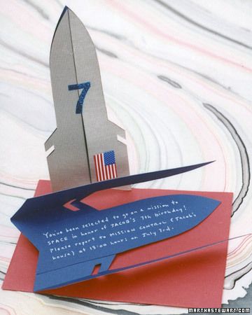 an origami rocket ship on top of a piece of red and blue paper