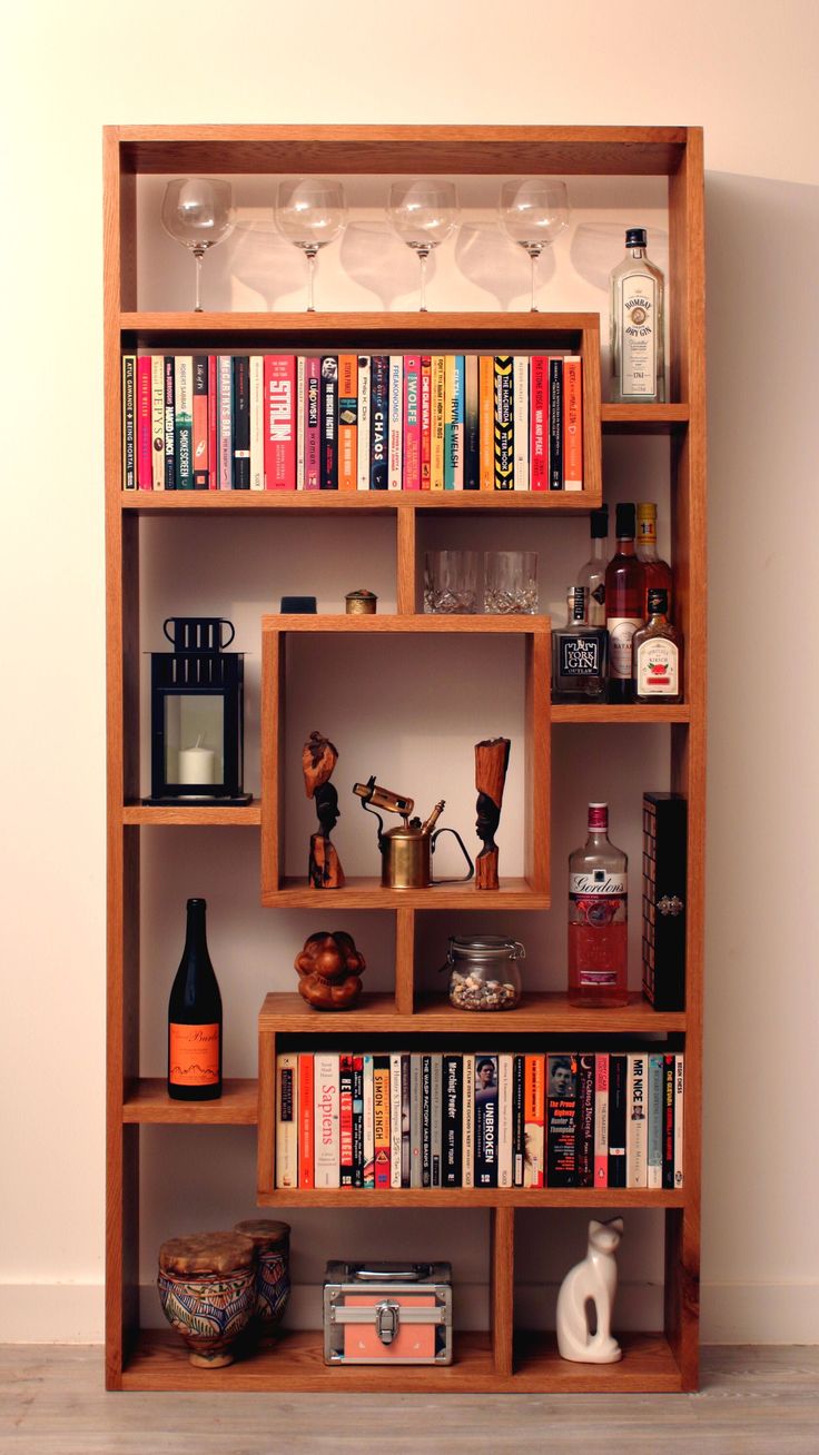 a bookshelf filled with lots of books and wine glasses on top of it