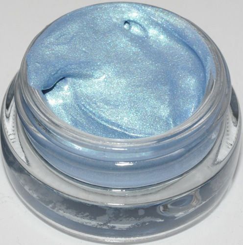 a jar of blue powder on a white surface with silver flecks in it