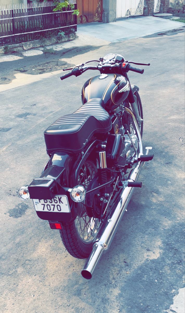 a black motorcycle parked on the street next to a fence