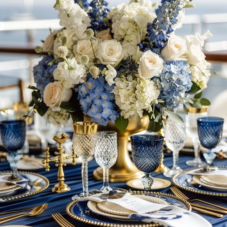 a blue and white table setting with gold place settings