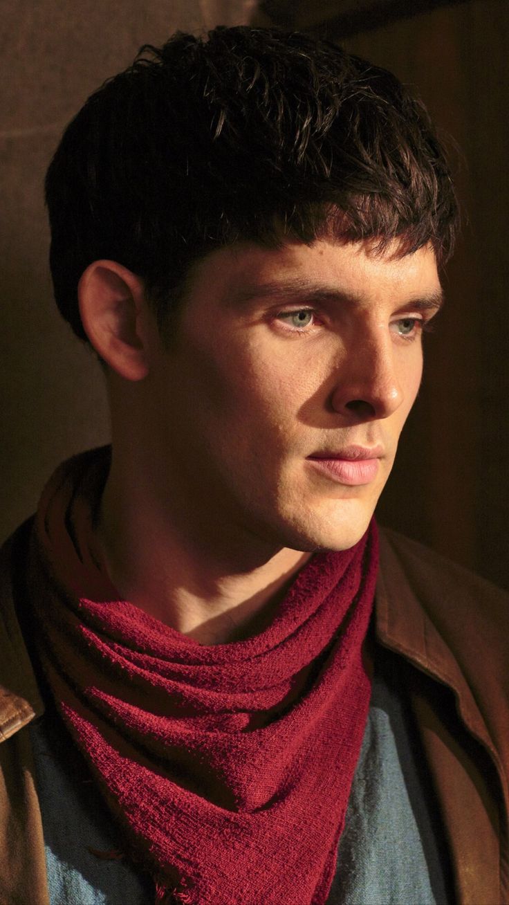 a young man wearing a red scarf looks into the distance with an intense look on his face