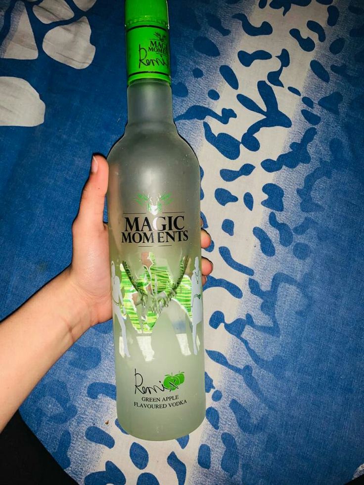 a person holding a bottle of alcohol on top of a blue and white table cloth