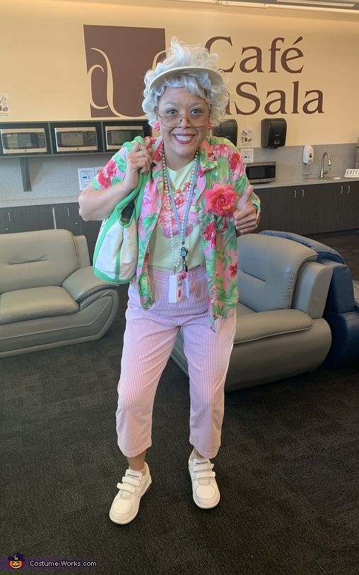 an older woman dressed in pink and green with flowers on her head, posing for the camera