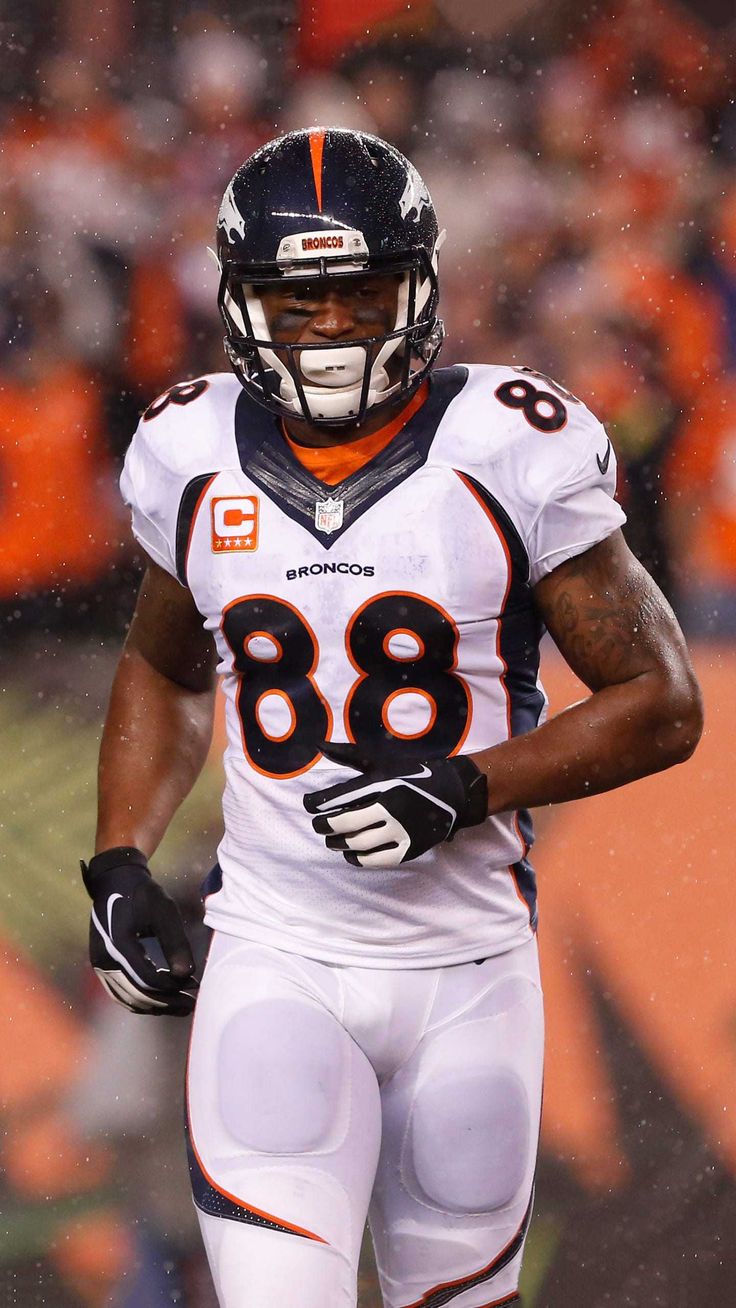 a football player in the rain with his hands on his hips and one eye closed