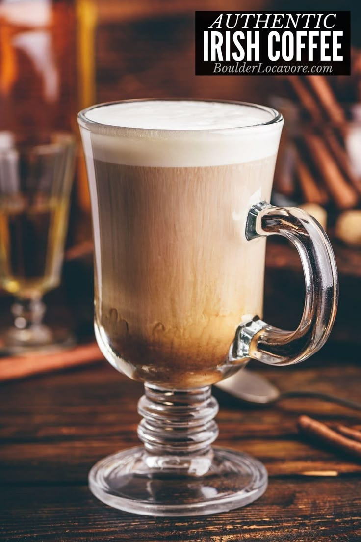 a glass cup filled with liquid sitting on top of a wooden table next to cinnamon sticks