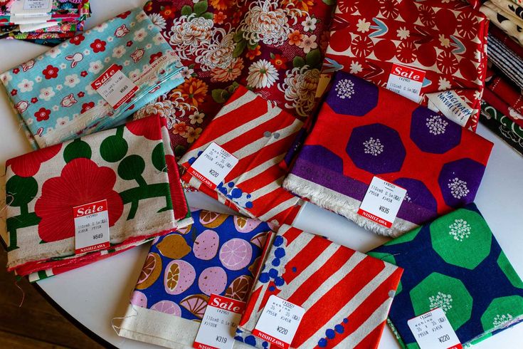 many different colored and patterned items on a white table with price tags attached to them