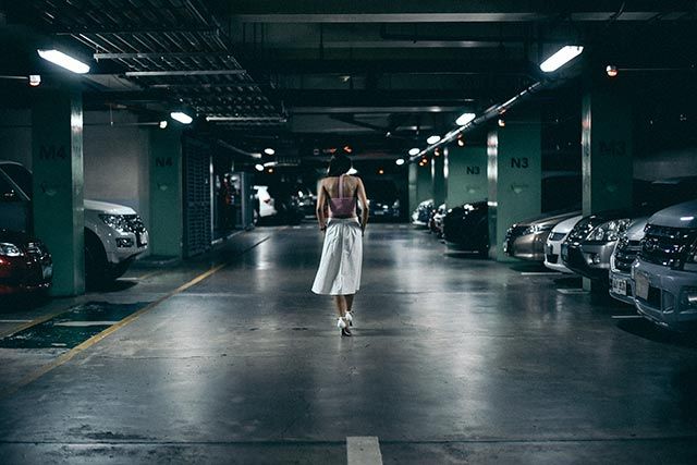 a woman walking down a dark parking garage