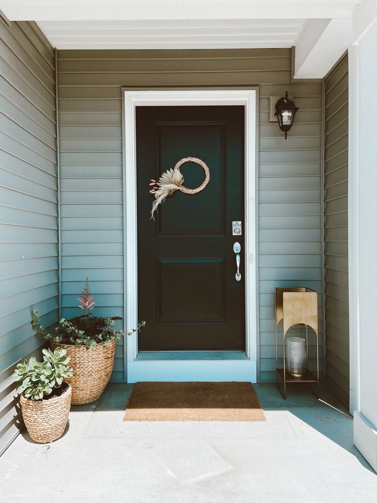 a blue front door with two planters on the side and a light brown basket next to it