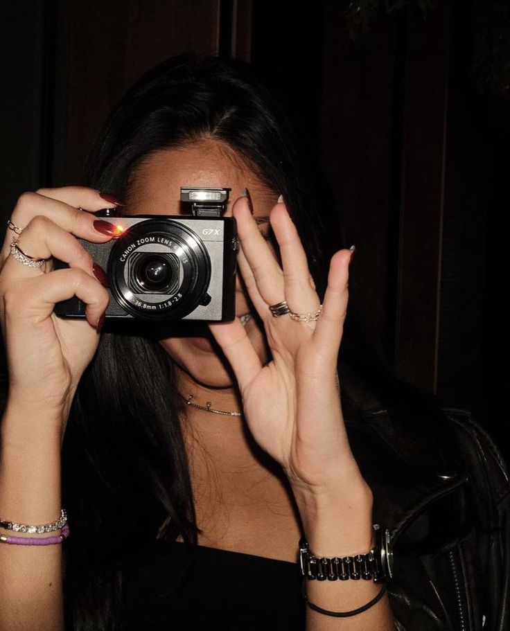 a woman holding up a camera to take a photo in front of her face with both hands