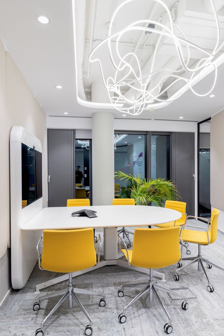 an office meeting room with yellow chairs and a white table in the middle of it