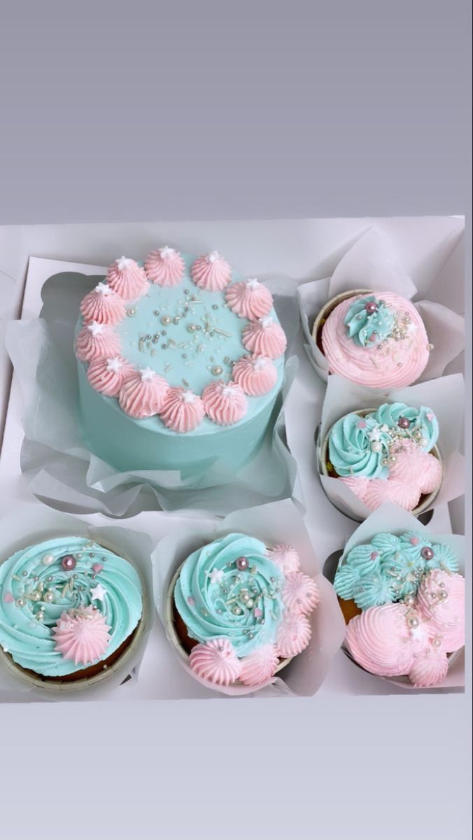 a box filled with lots of cupcakes covered in pink and blue frosting