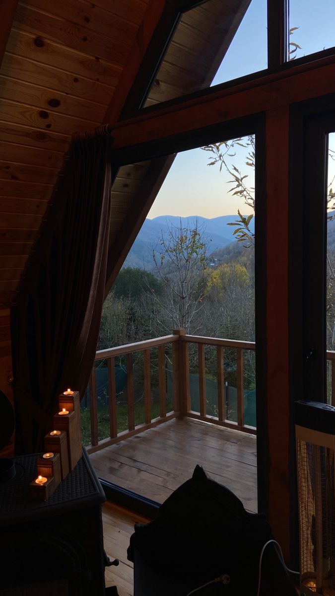 the view from inside a cabin looking out at mountains and trees, with candles lit on the porch