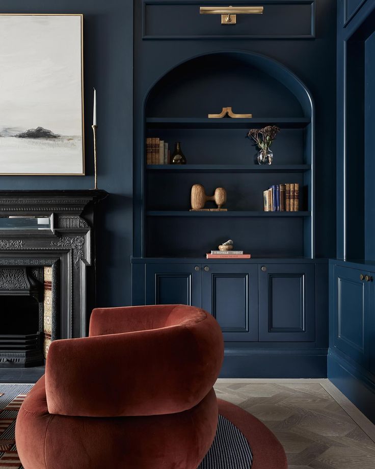 a living room with dark blue walls and an orange chair in front of a fireplace