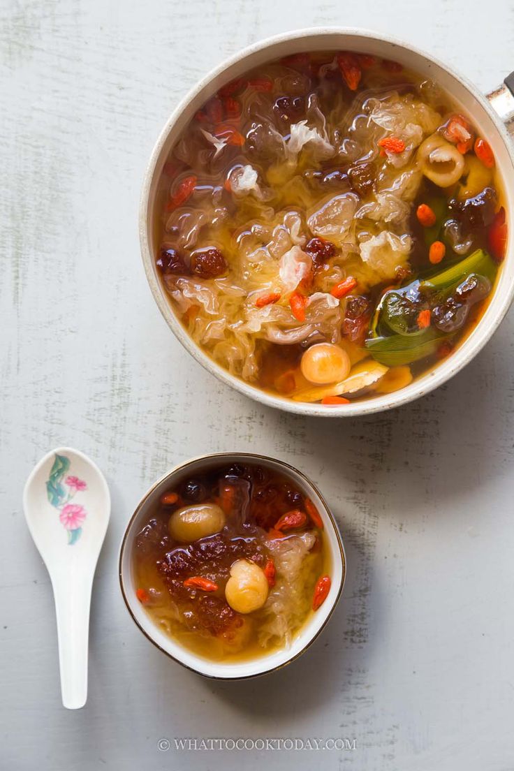 two bowls filled with soup next to spoons