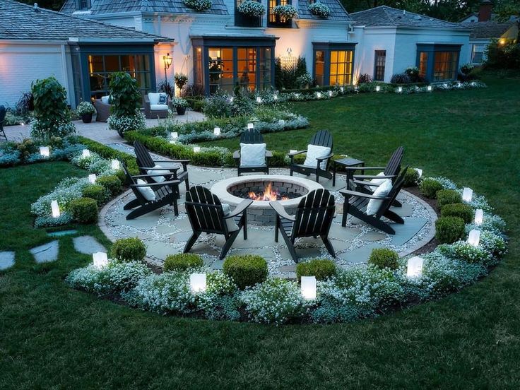 an outdoor fire pit surrounded by chairs and lights