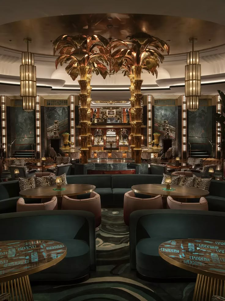 the interior of a fancy restaurant with green couches and gold chandeliers