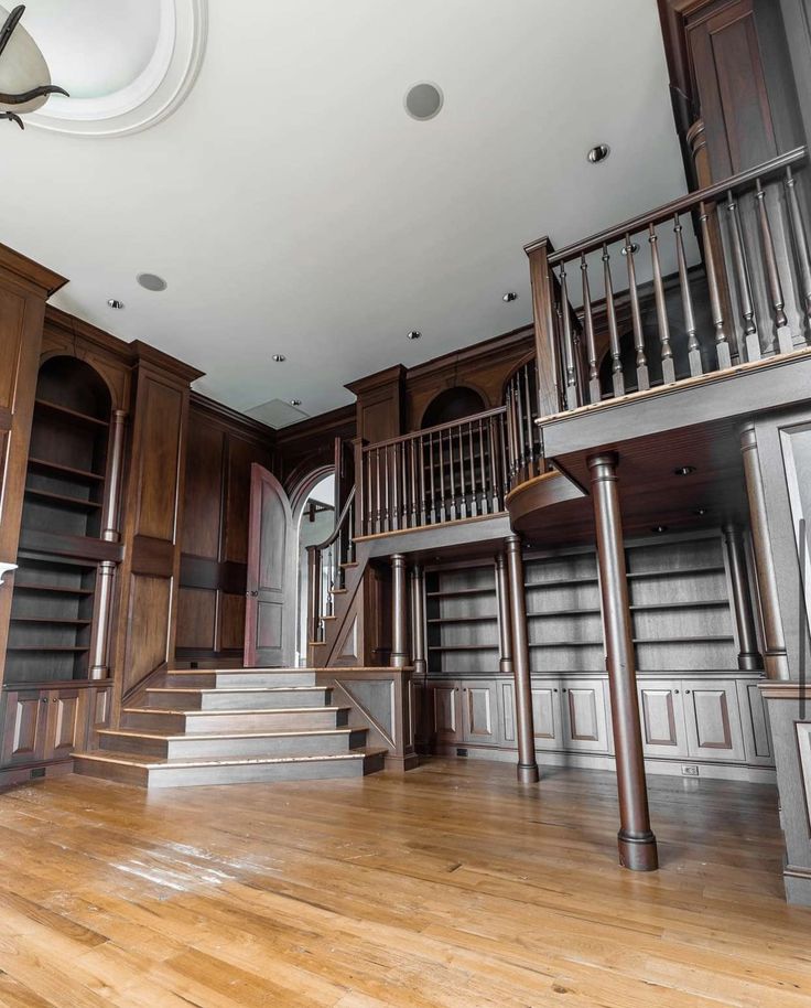 an empty room with wooden floors and bookshelves in the center, surrounded by wood paneling