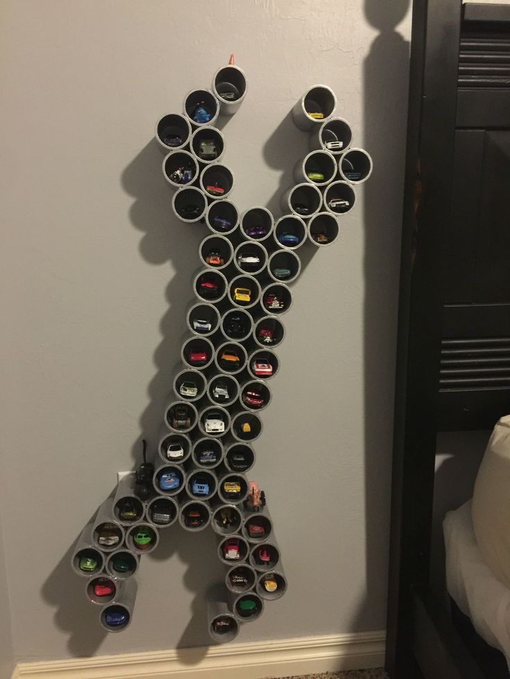 a large metal letter made out of cans on the side of a wall next to a bed