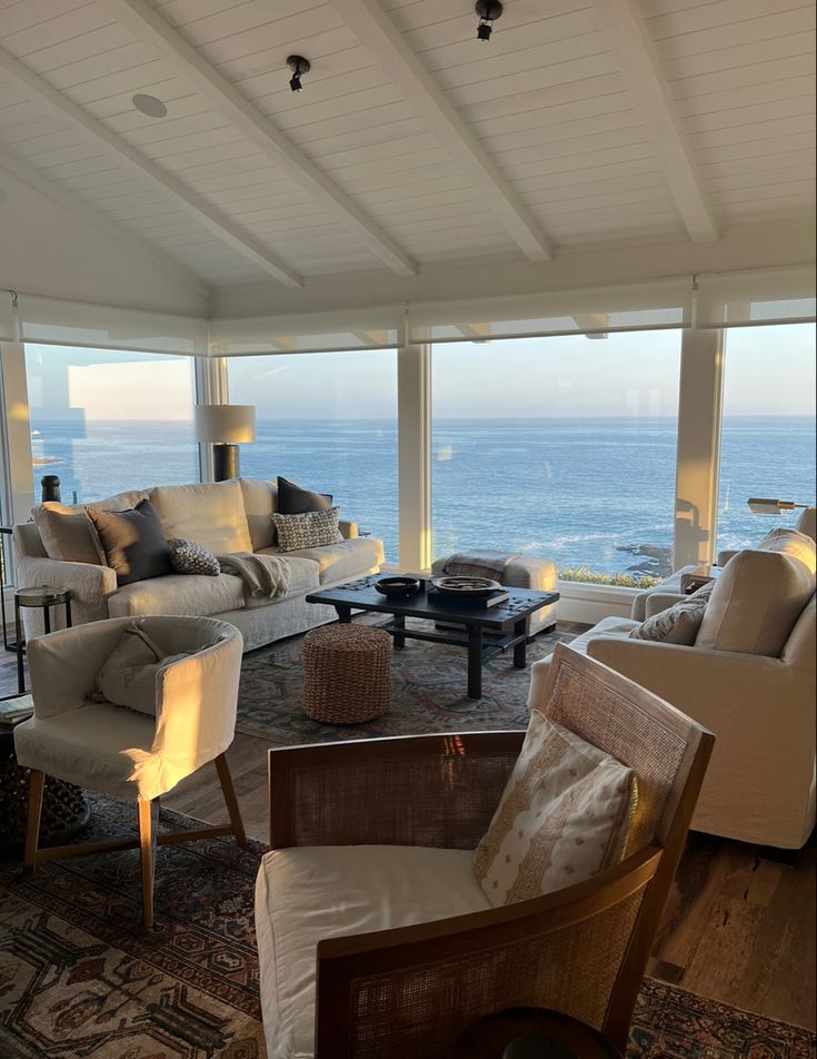 a living room filled with furniture and large windows overlooking the ocean in front of it