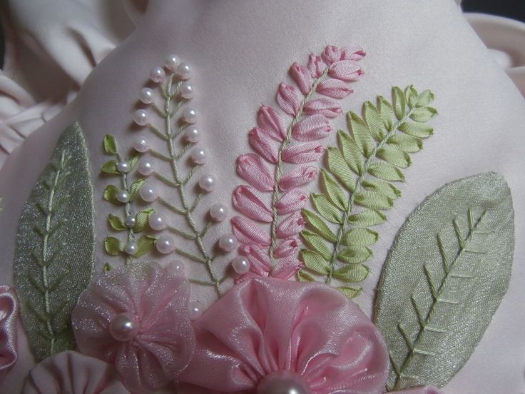 a white vase with pink flowers and green leaves on it