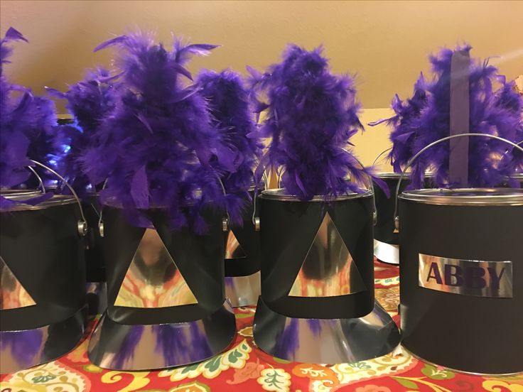 purple feathers are placed in buckets on a table