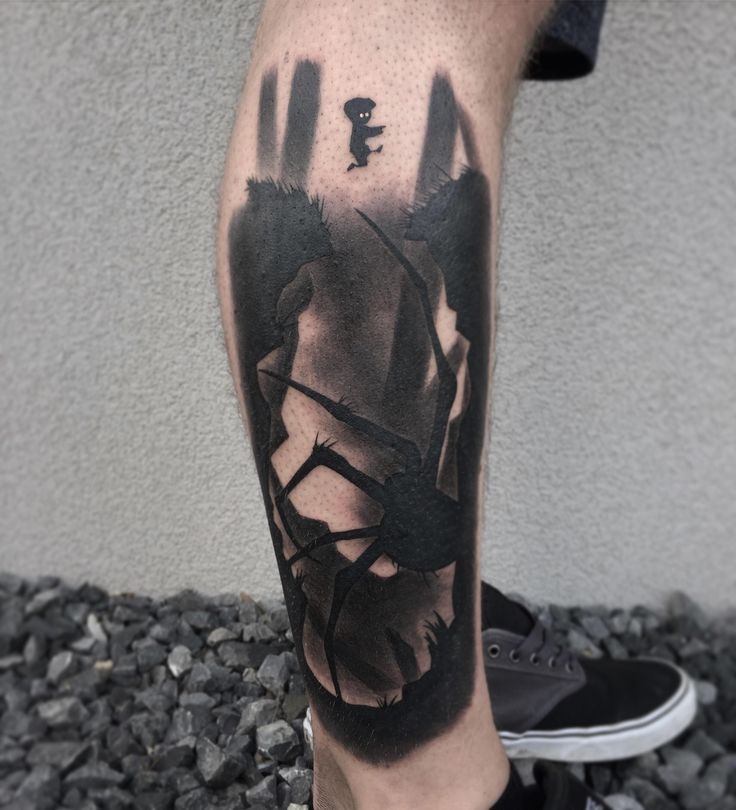 a man's leg with a black and grey ink tattoo on it, which has an image of a hand holding a key