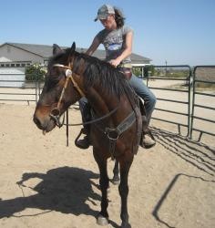 a woman riding on the back of a brown horse next to a man wearing a hat