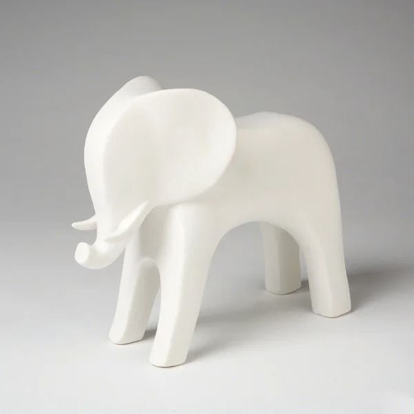 a white elephant figurine sitting on top of a gray table next to a wall