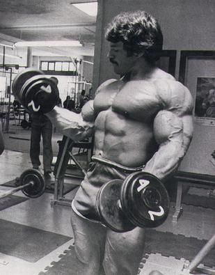 a man in the gym holding two dumbs