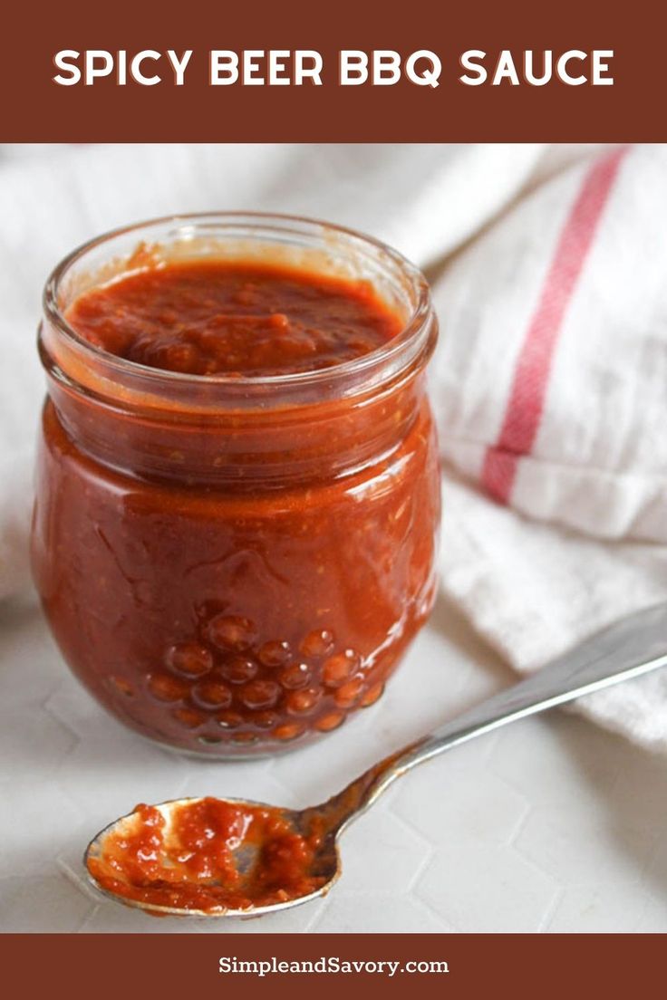 a glass jar filled with bbq sauce next to a spoon