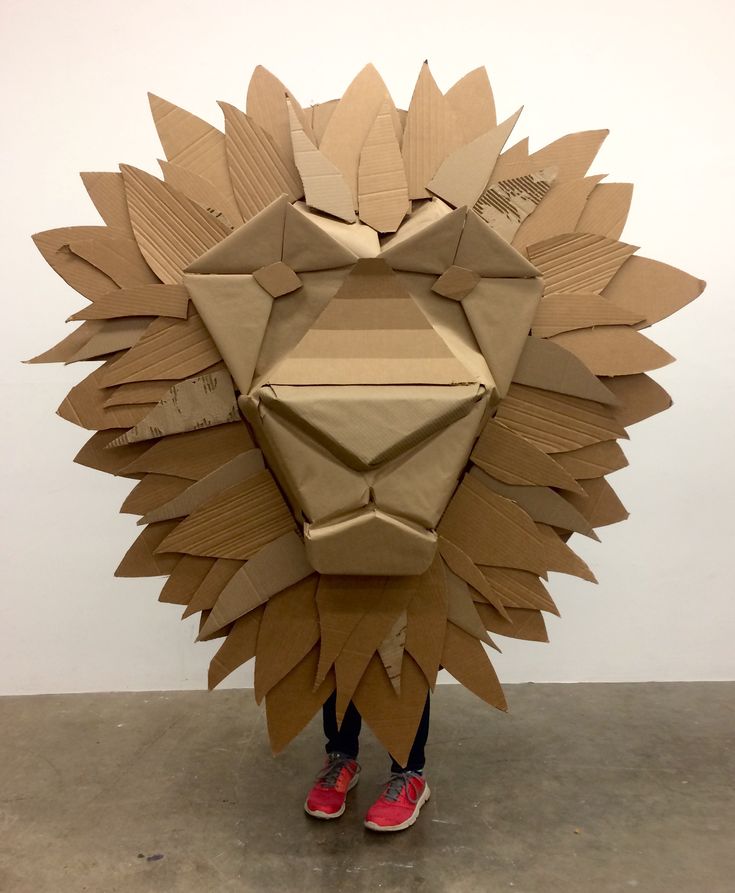 a person standing in front of a cardboard lion head