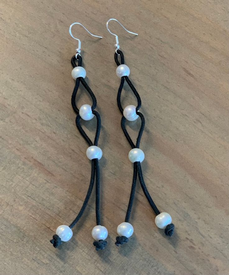 two pairs of black and white beaded earrings on a wooden table with beads hanging from them