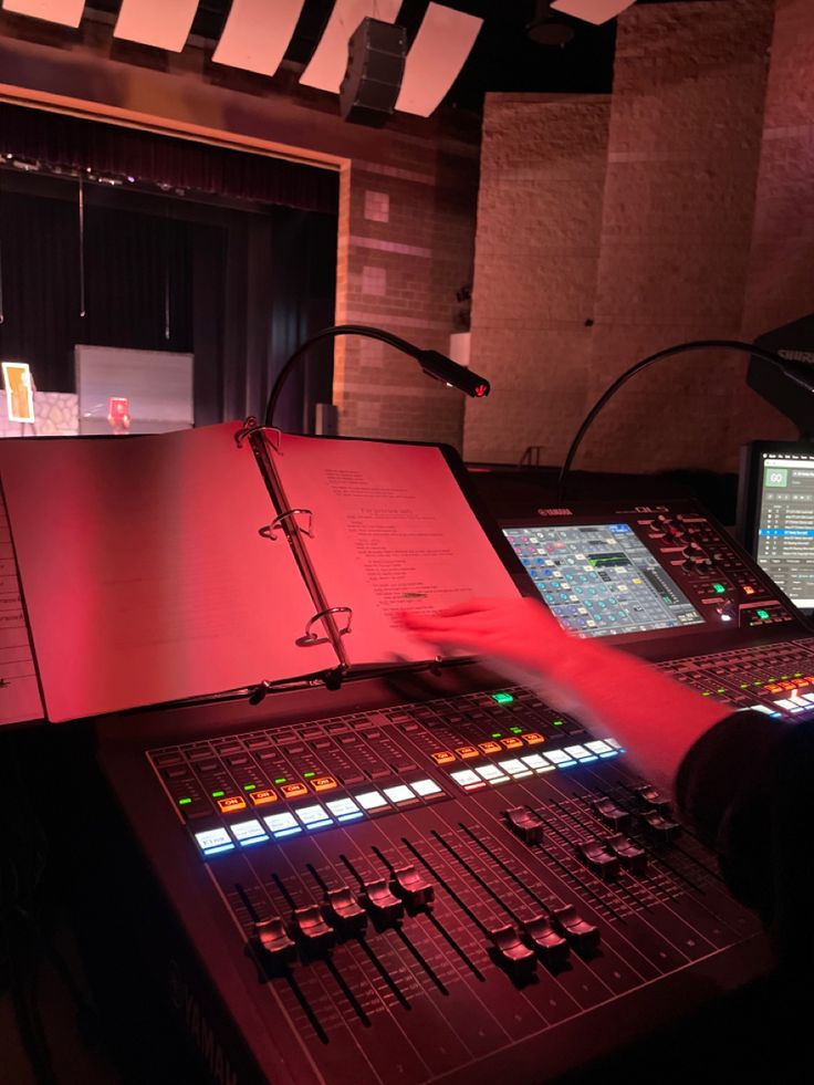 a person is working on an audio mixing console in a recording studio with red lighting