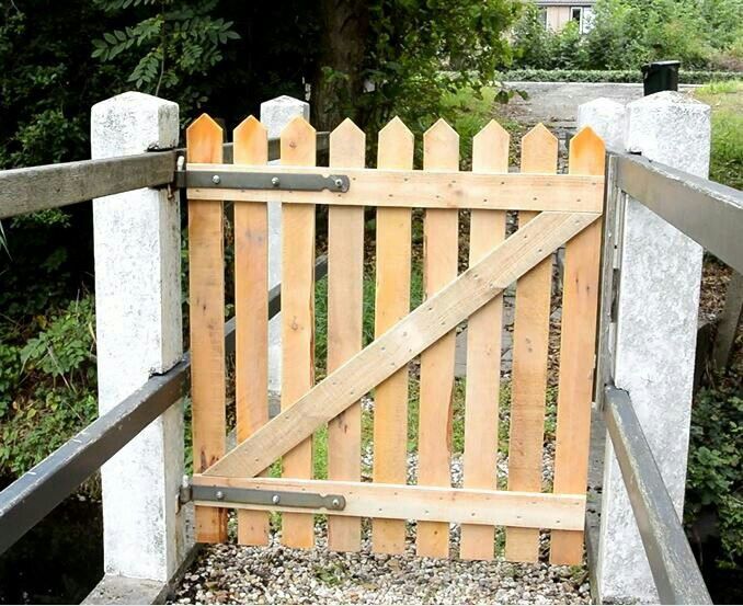 a wooden gate is opened to allow people to enter the yard or garden area,