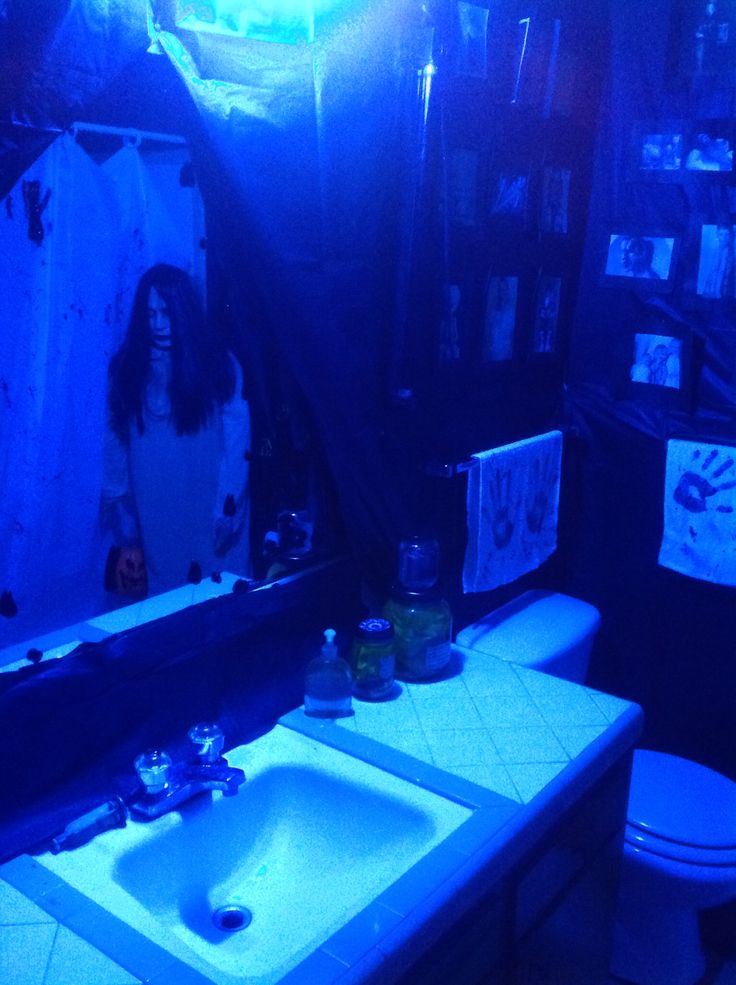 a bathroom with a sink, toilet and mirror lit up by blue light in the dark