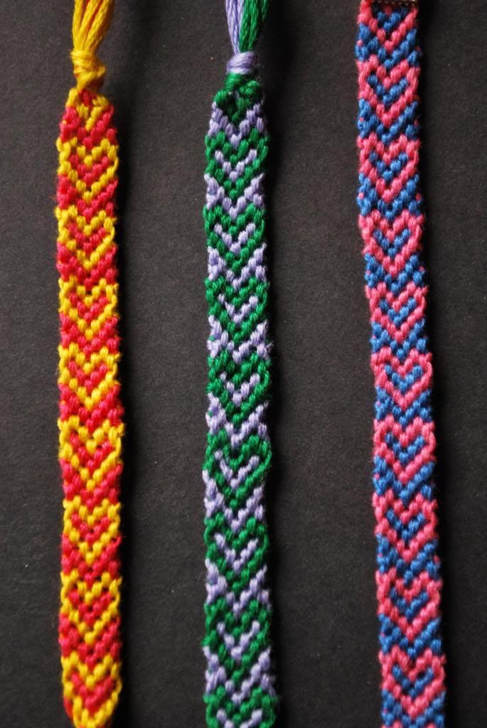 three different colored bracelets on a black surface