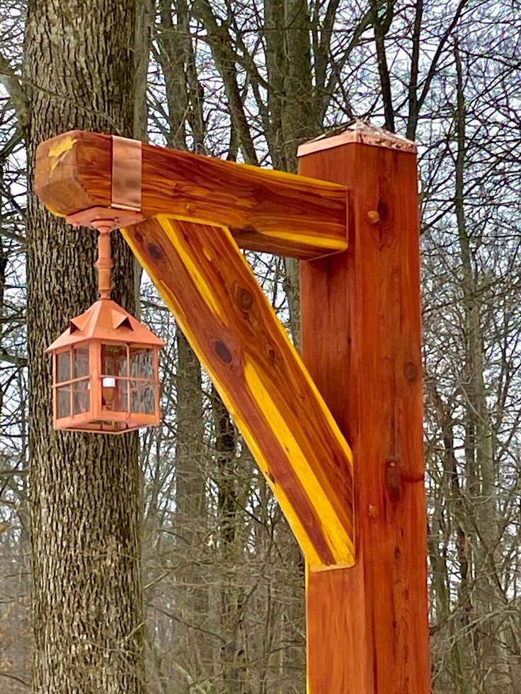 a wooden structure with a lantern hanging from it's side in front of some trees