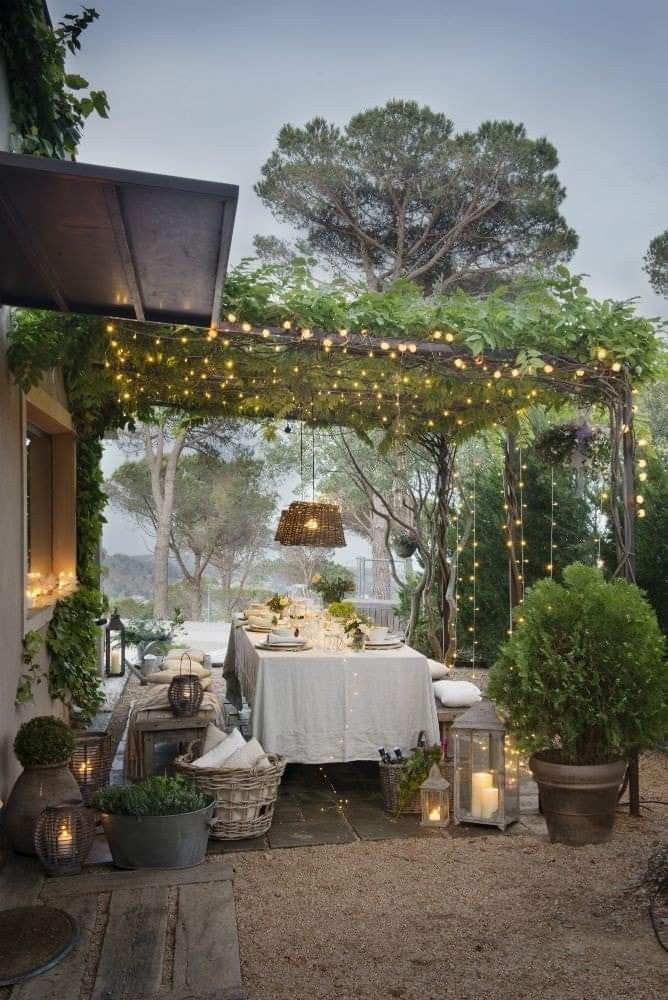 an outdoor dining area is decorated with lights and greenery