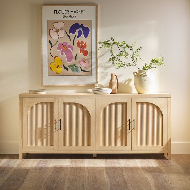 a wooden cabinet with two vases and a painting on the wall in front of it